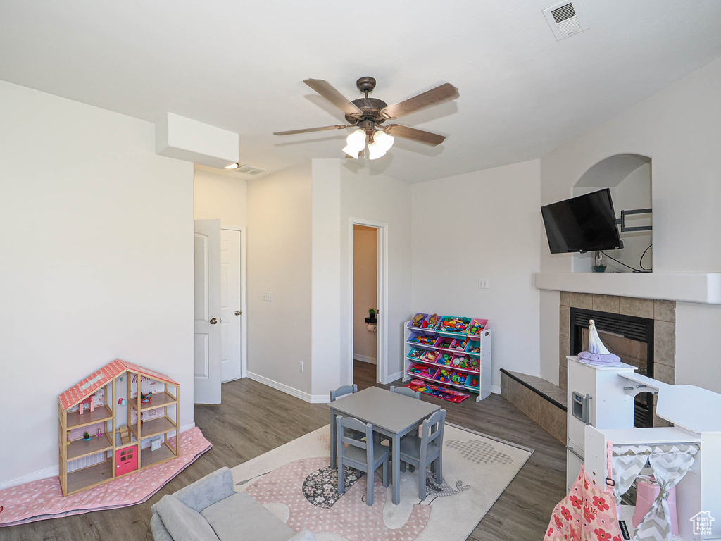 Recreation room with wood finished floors, a fireplace, and ceiling fan