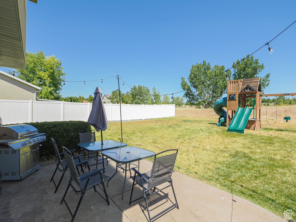 View of patio featuring area for grilling, a playground, and outdoor dining space