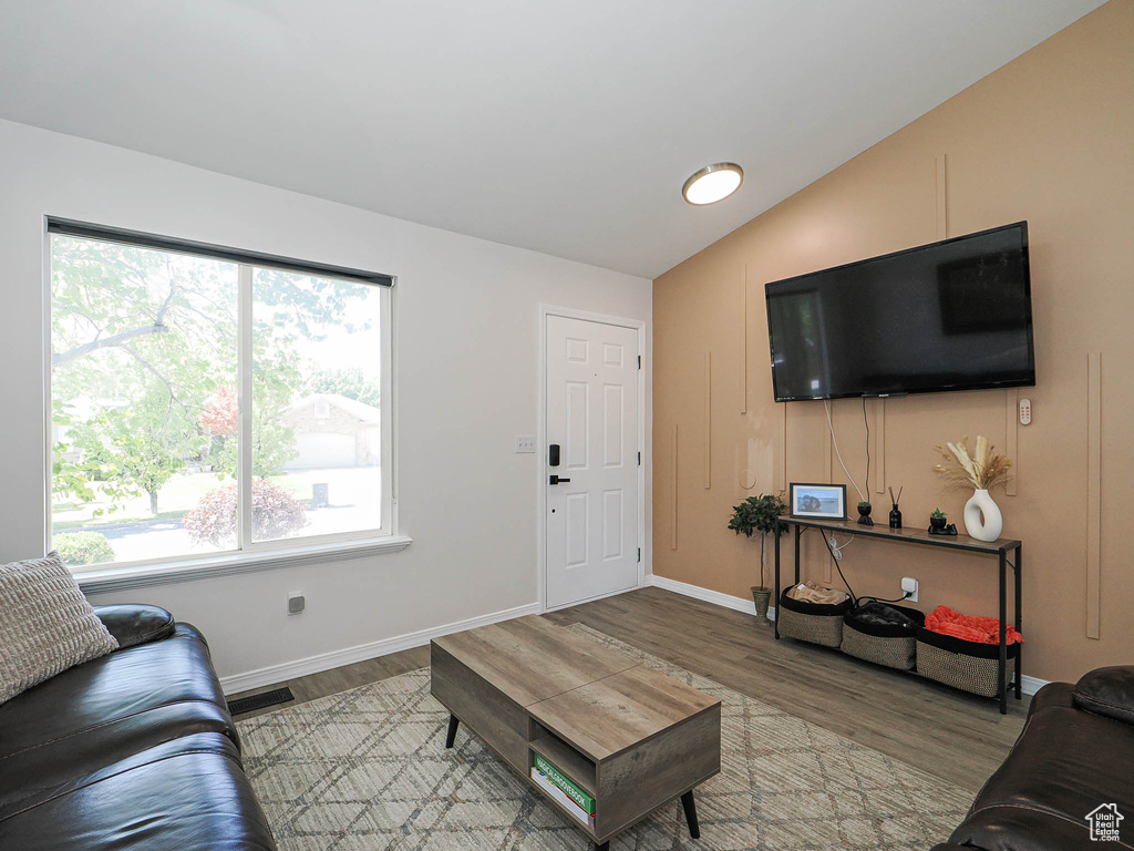 Living area with wood finished floors and vaulted ceiling