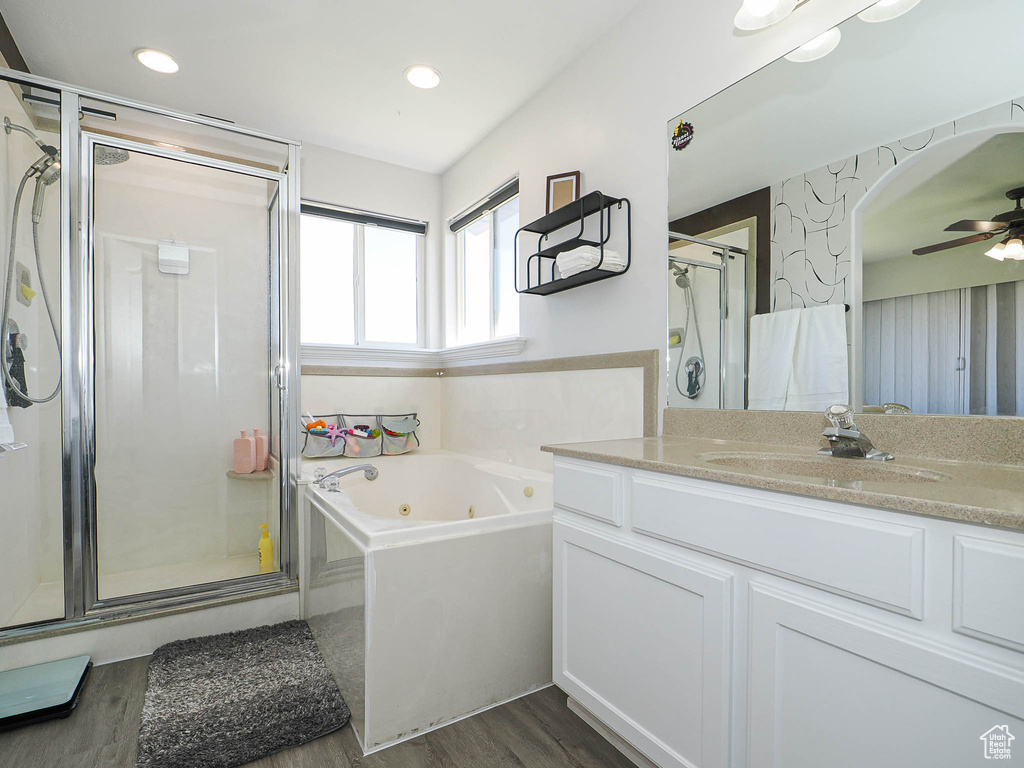 Bathroom featuring wood finished floors, a stall shower, a whirlpool tub, vanity, and a ceiling fan