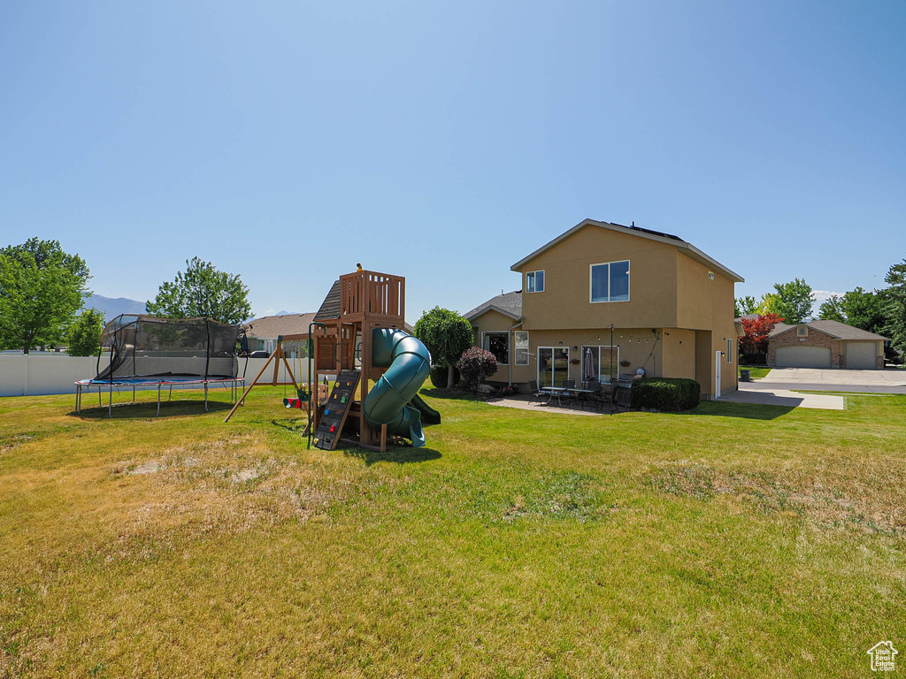View of yard featuring a trampoline and a playground