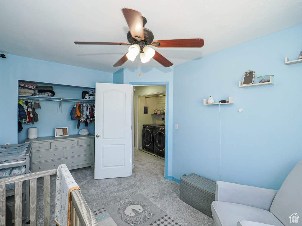 Carpeted bedroom with washer and dryer, a ceiling fan, and a closet