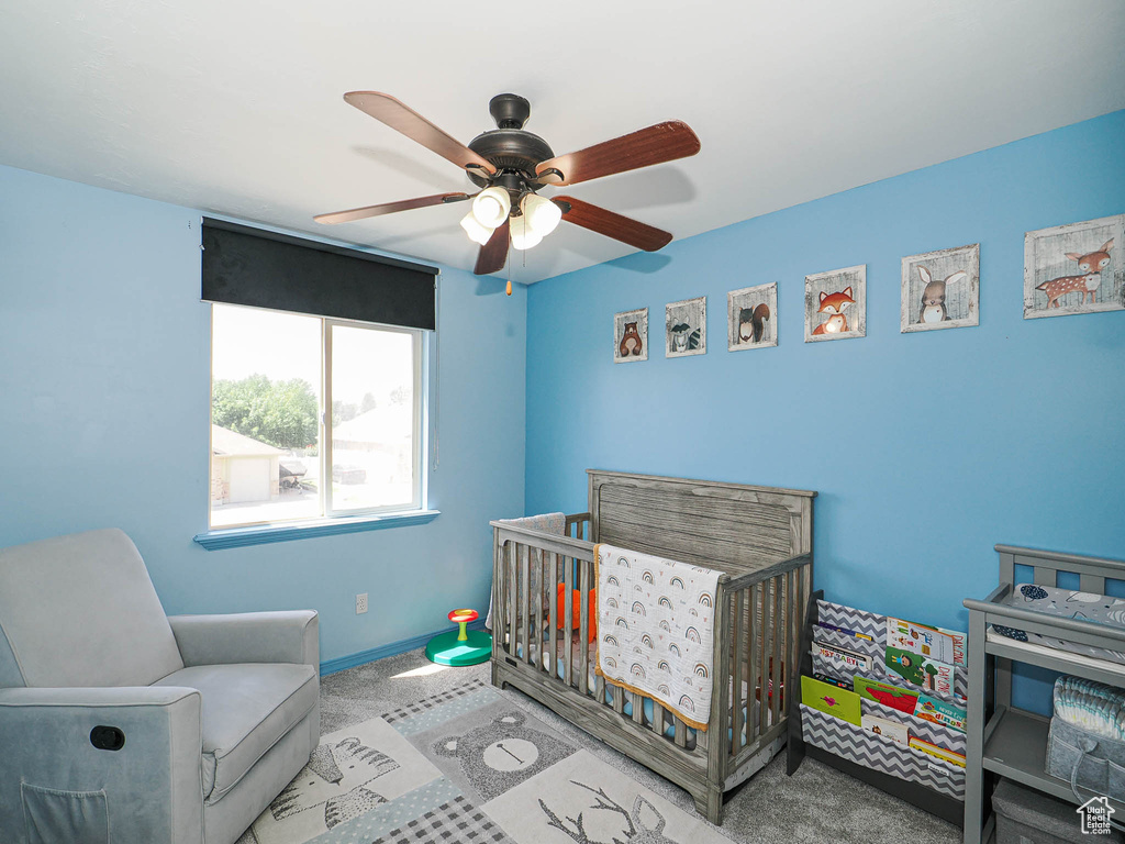 Carpeted bedroom with a nursery area and ceiling fan