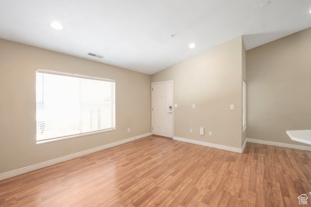 Empty room featuring lofted ceiling, light wood-style floors, and recessed lighting