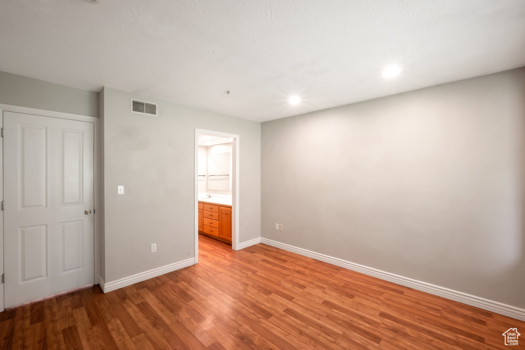 Unfurnished bedroom with light wood-style floors, connected bathroom, and recessed lighting