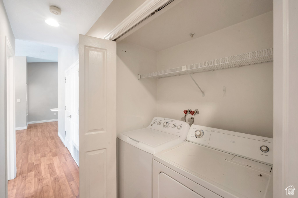 Washroom featuring washing machine and dryer and light wood-style floors