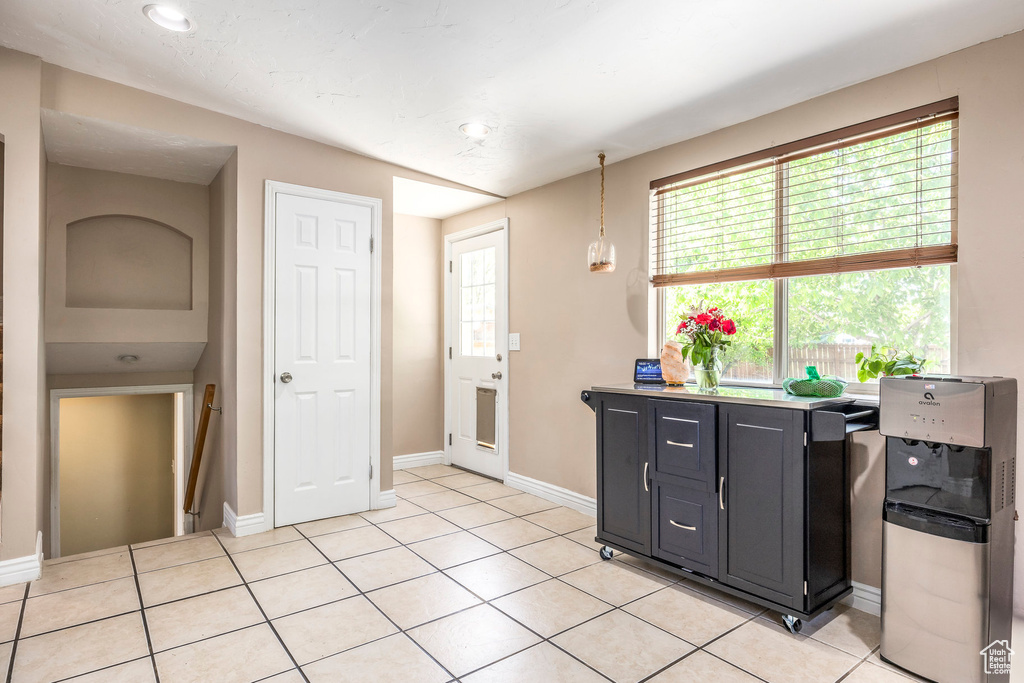 Kitchen with light tile patterned flooring, dark cabinets, recessed lighting, and decorative light fixtures