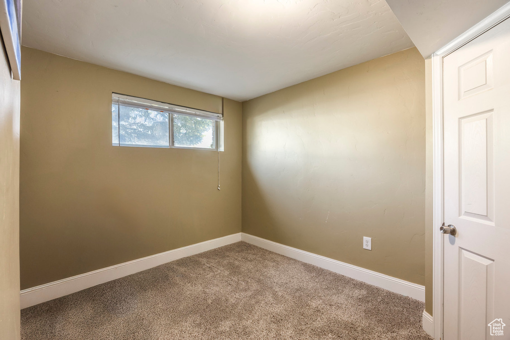 Carpeted spare room featuring baseboards