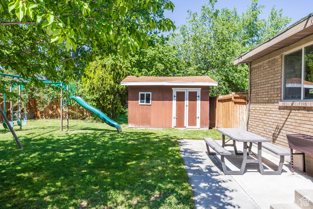 View of yard with a storage unit, a playground, and a patio