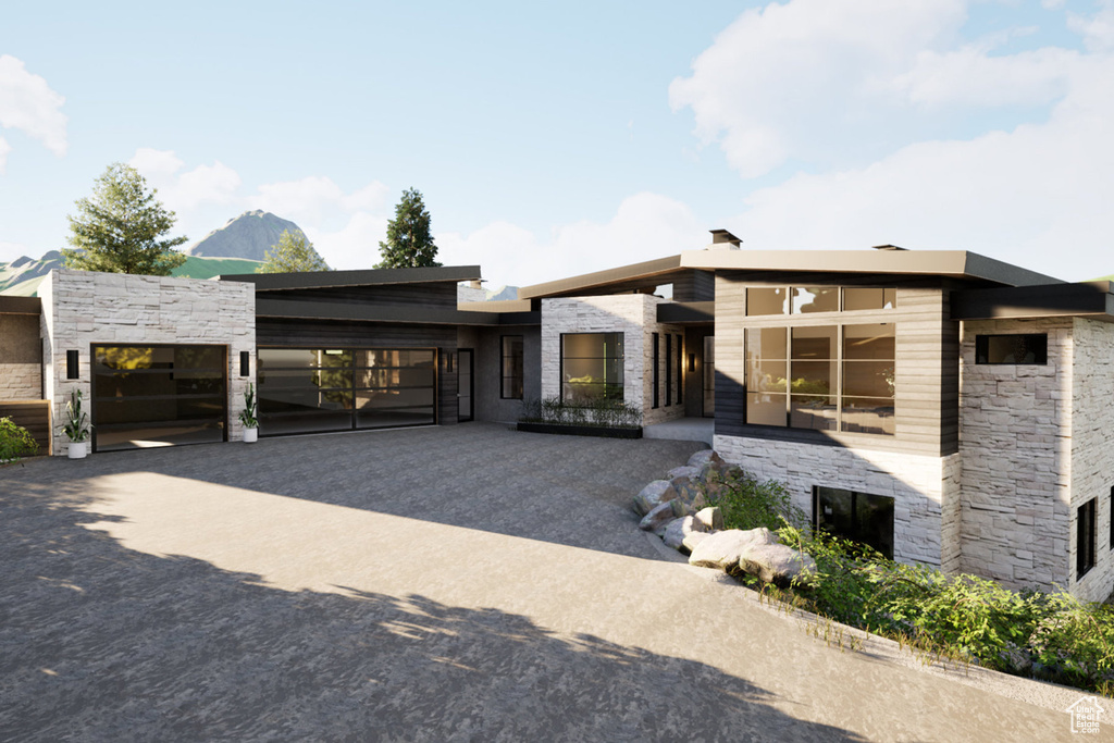 Contemporary home with stone siding, driveway, and a garage