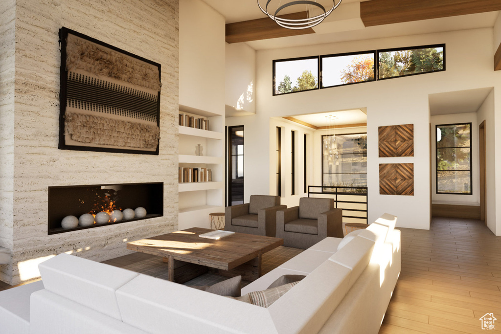 Living room featuring a towering ceiling, built in features, a chandelier, wood finished floors, and a fireplace