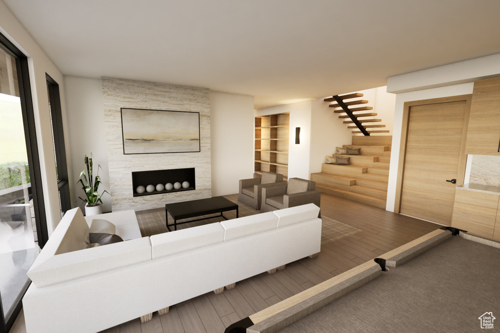 Living area featuring a stone fireplace, stairway, and wood finished floors