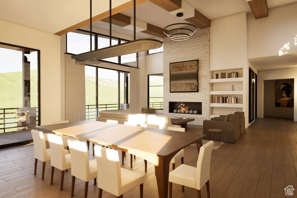 Dining room featuring a chandelier, a high ceiling, wood finished floors, beamed ceiling, and a stone fireplace
