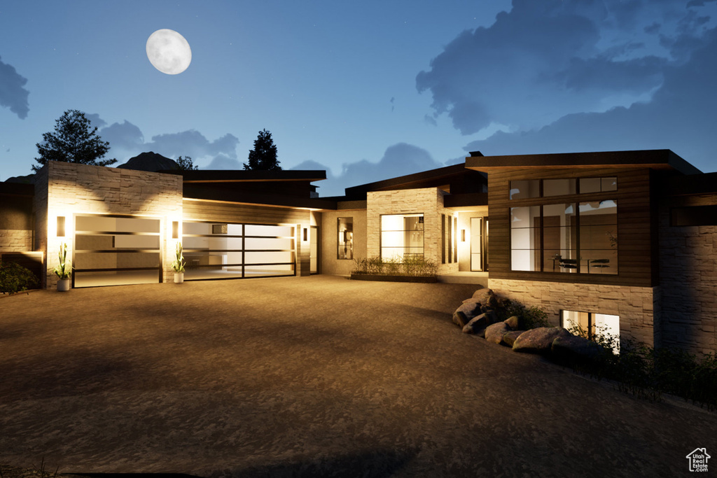 Contemporary house with stone siding, a garage, and driveway