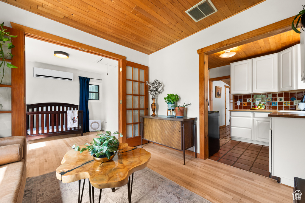 Living room with a wall unit AC, wood ceiling, and light wood-type flooring