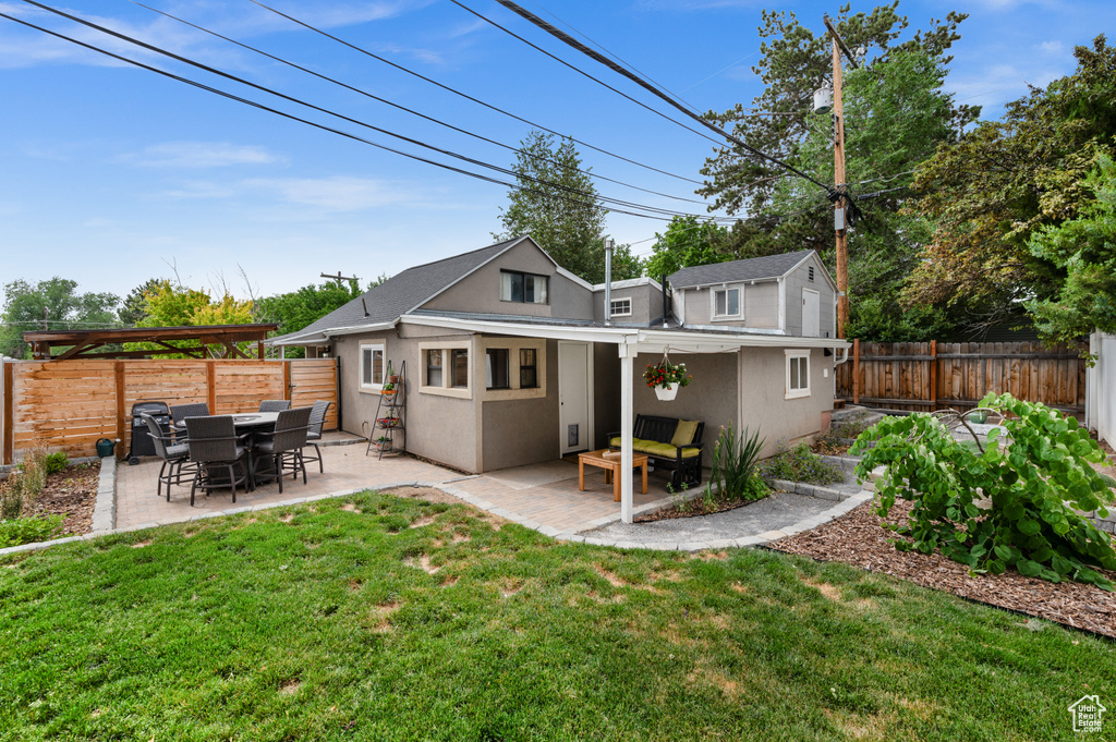 Rear view of house with stucco siding, a fenced backyard, and a patio