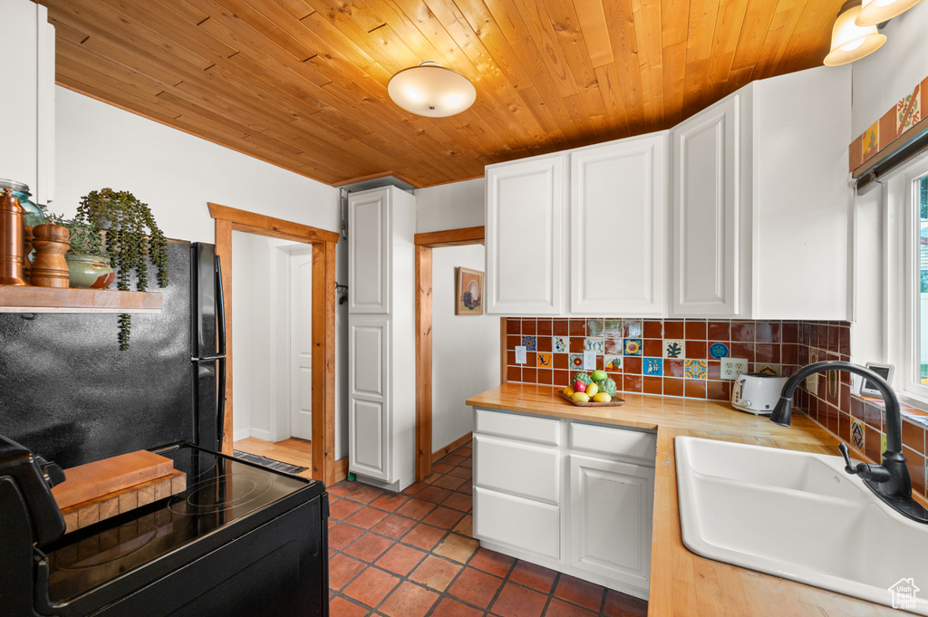 Kitchen with black appliances, wood ceiling, backsplash, white cabinetry, and tile patterned flooring