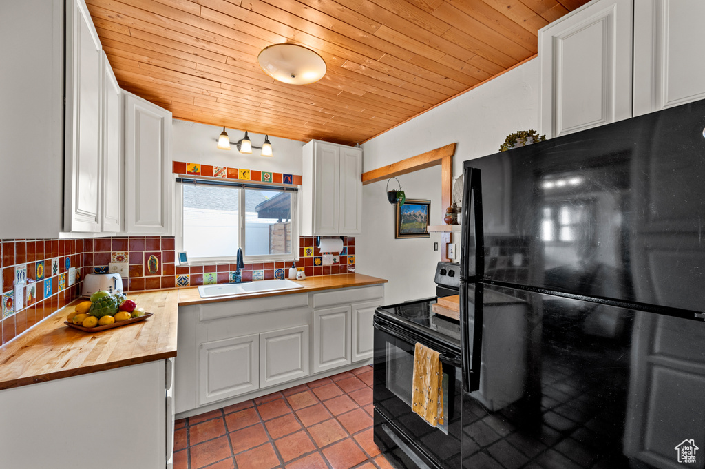 Kitchen featuring black appliances, wood counters, wood ceiling, backsplash, and white cabinetry