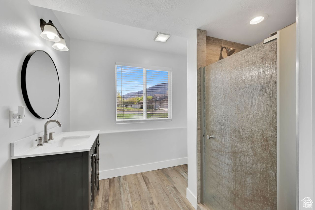Full bath featuring vanity, wood finished floors, a shower stall, and recessed lighting