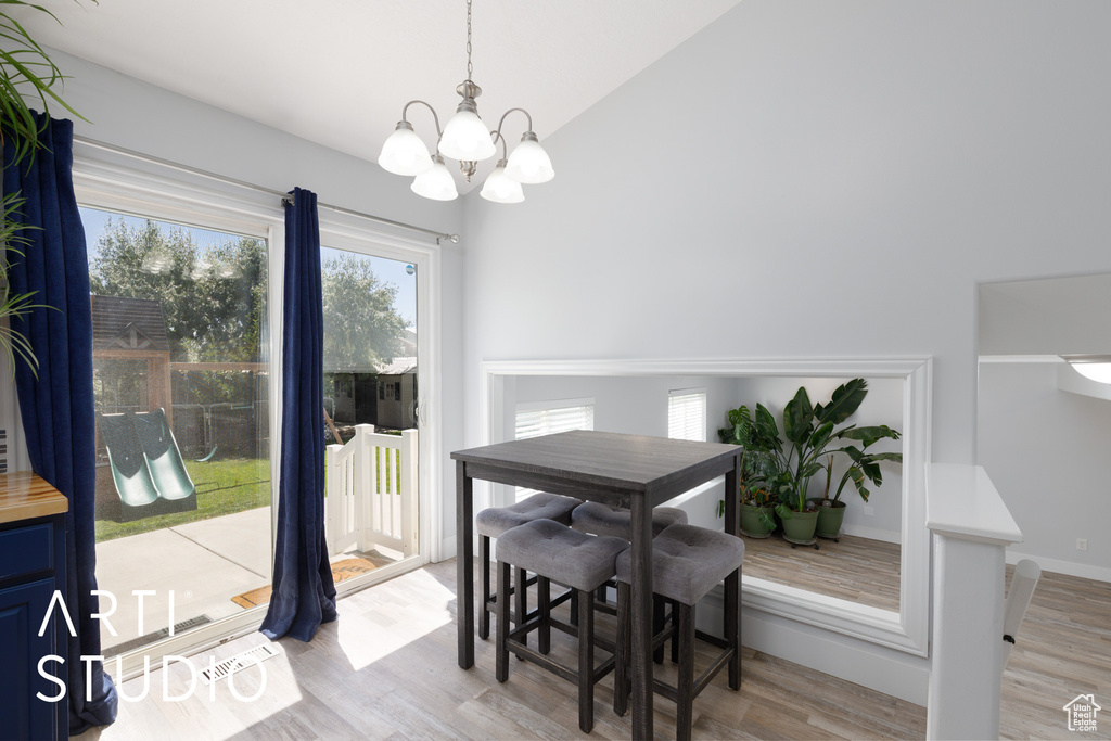 Dining space featuring a chandelier, light wood finished floors, and lofted ceiling