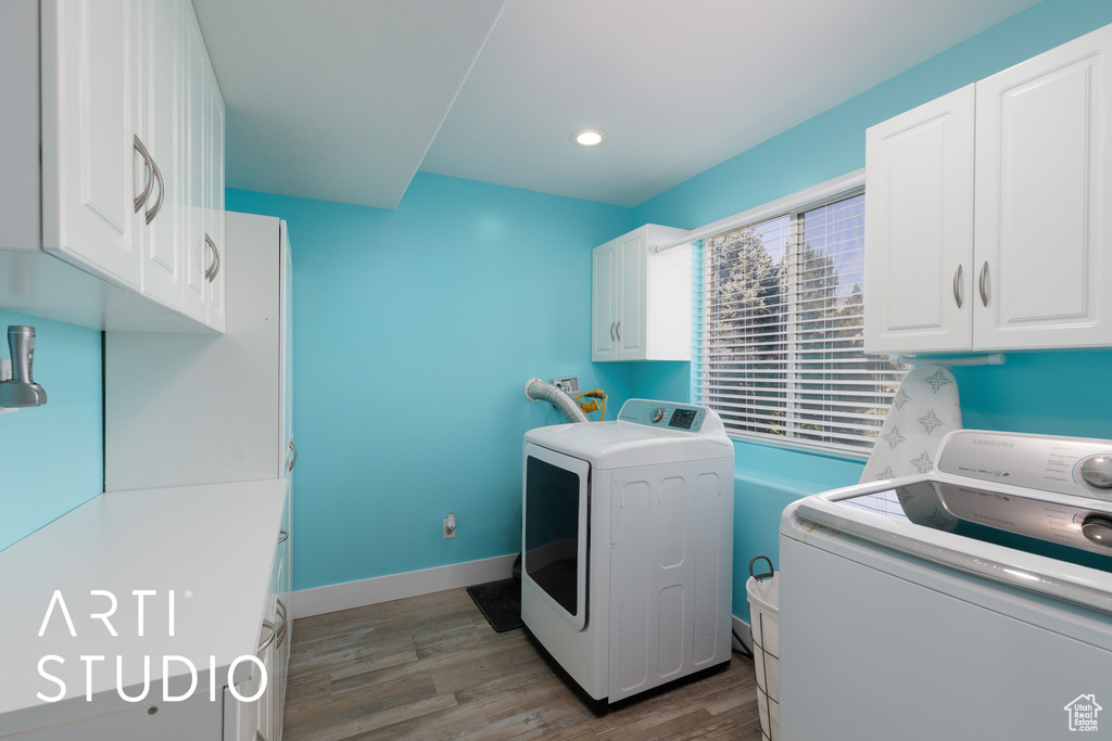 Laundry room with cabinet space, washer and dryer, wood finished floors, and recessed lighting