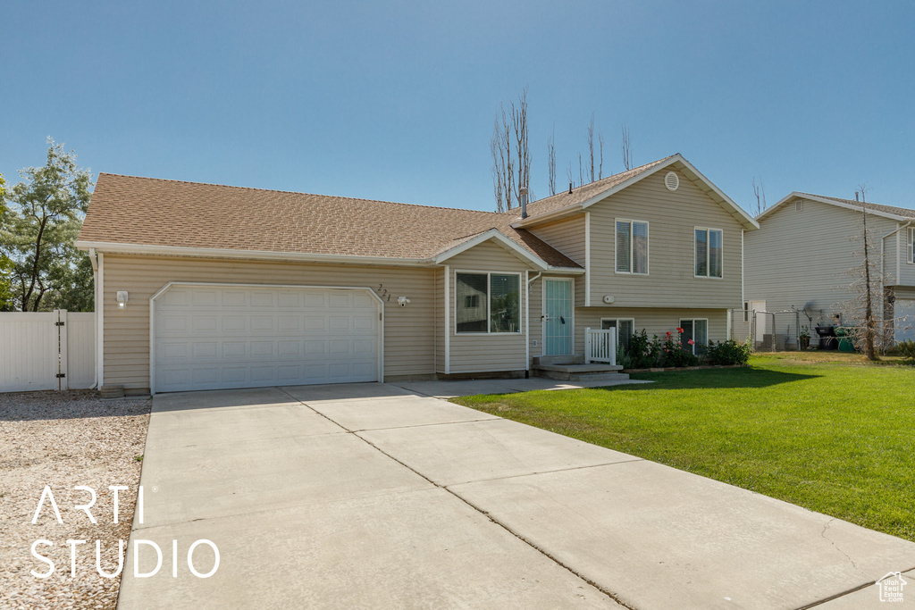 Split level home featuring driveway, a garage, and a gate