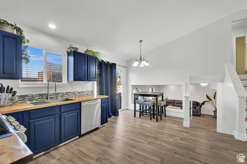 Kitchen featuring wood counters, dishwasher, blue cabinetry, plenty of natural light, and vaulted ceiling