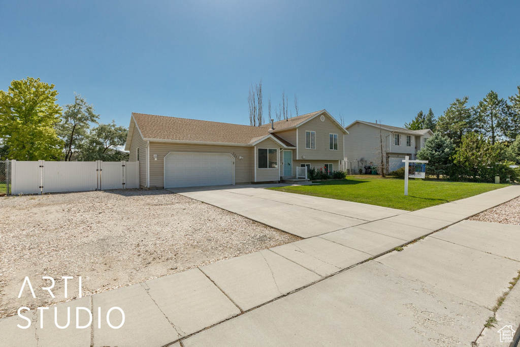 Tri-level home featuring concrete driveway, a gate, and a garage