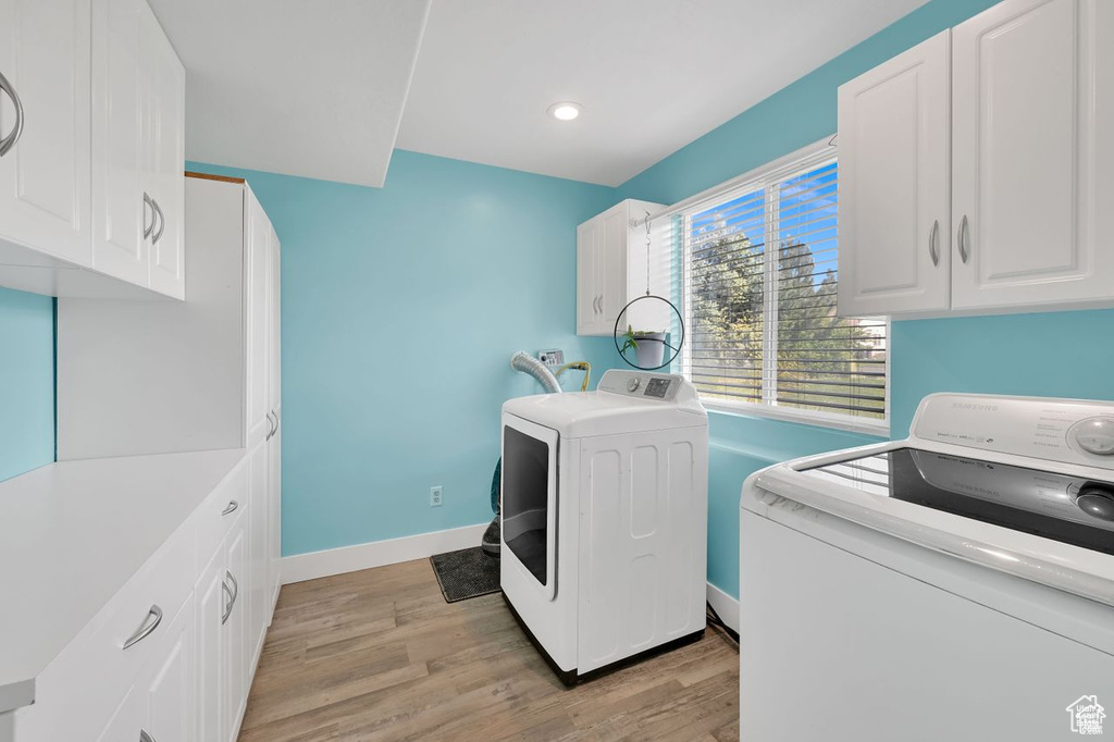 Laundry area featuring washing machine and clothes dryer, cabinet space, light wood finished floors, and recessed lighting