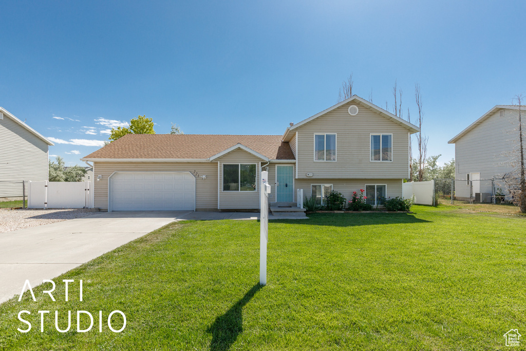 Split level home with an attached garage, driveway, and a gate