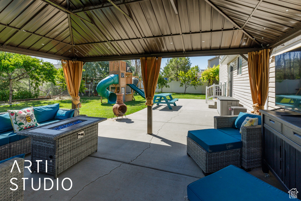 Fenced backyard featuring a gazebo, an outdoor living space with a fire pit, a playground, and a patio area