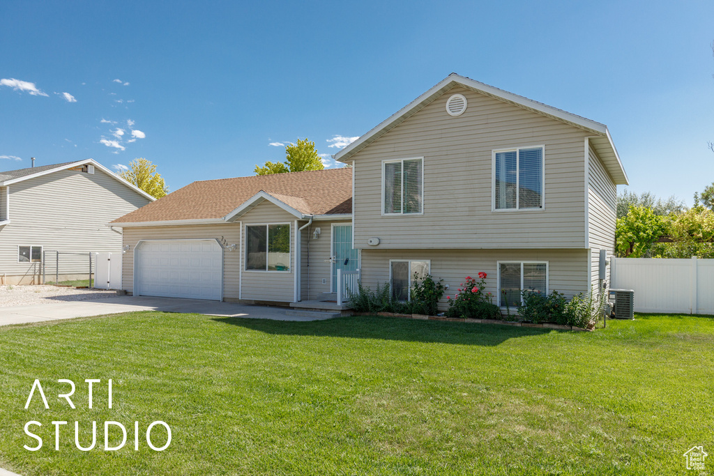 Split level home featuring driveway, an attached garage, and a shingled roof