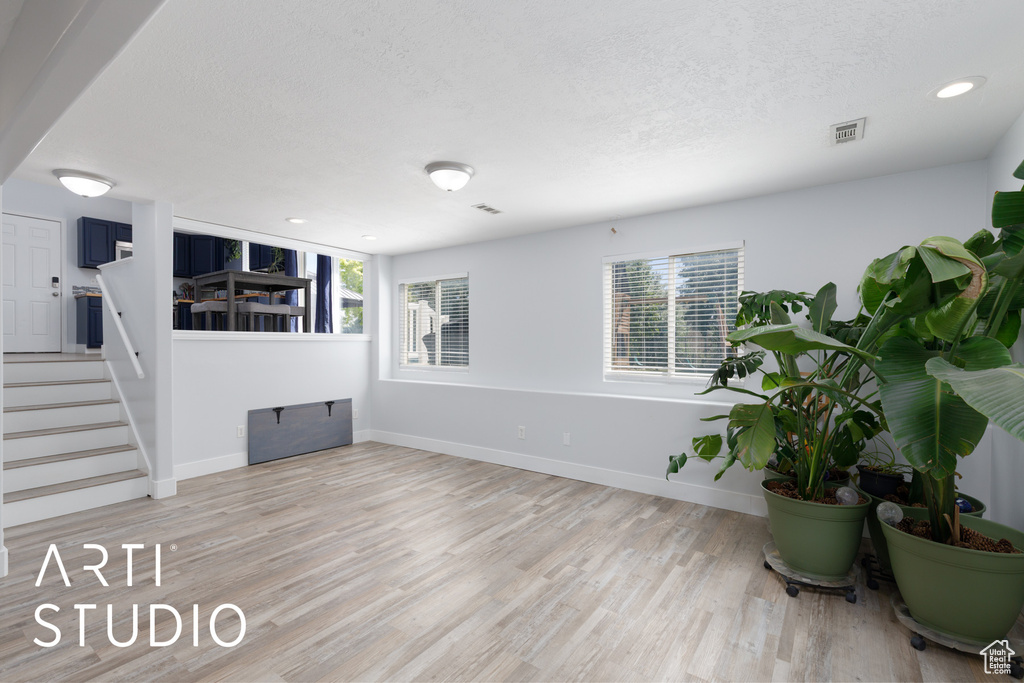 Living room featuring a textured ceiling, light wood-style flooring, stairway, and recessed lighting