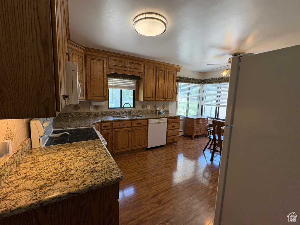 Kitchen with white appliances, a ceiling fan, tasteful backsplash, and dark wood-type flooring