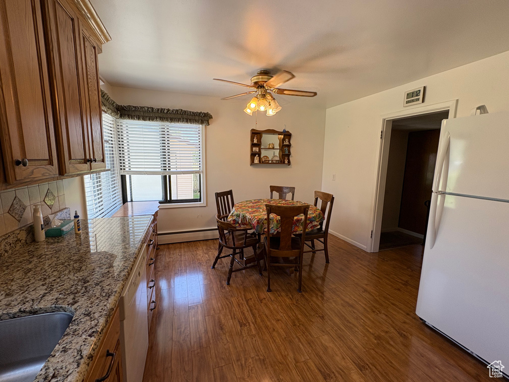 Dining area featuring a ceiling fan, dark wood-style flooring, and a baseboard heating unit
