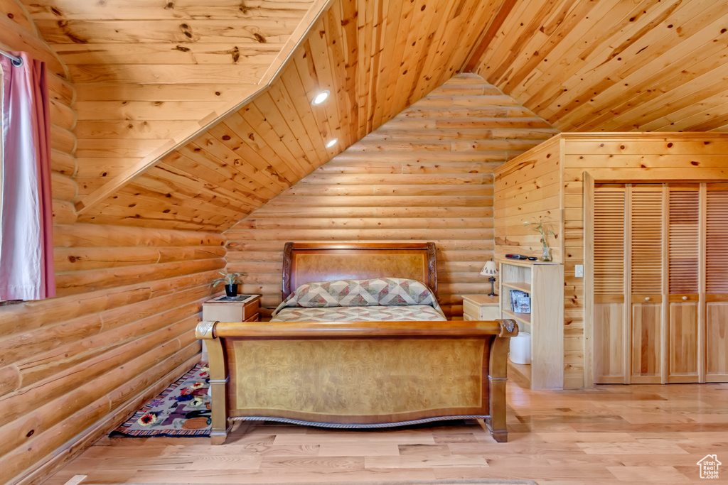 Bedroom featuring log walls, vaulted ceiling, wood ceiling, and wood finished floors