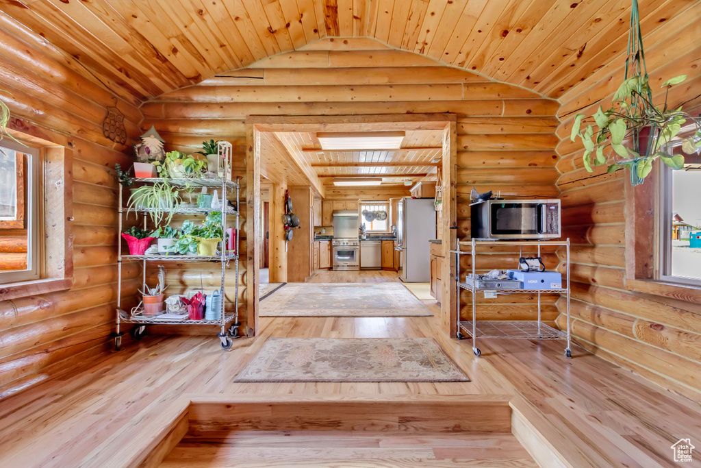 Entryway featuring vaulted ceiling, hardwood / wood-style flooring, wooden ceiling, and rustic walls