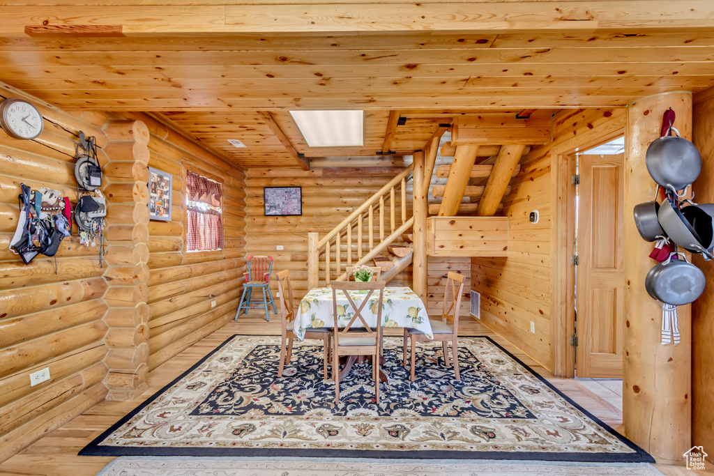 Dining area with rustic walls, wood ceiling, stairs, and wood finished floors