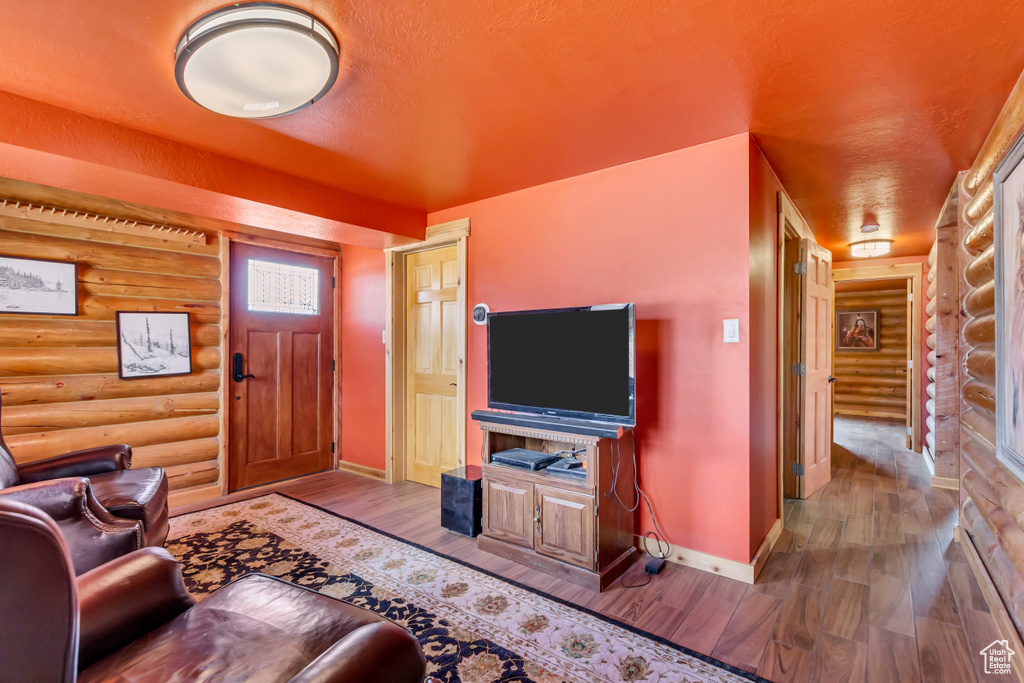 Living room featuring log walls, wood finished floors, and a textured ceiling