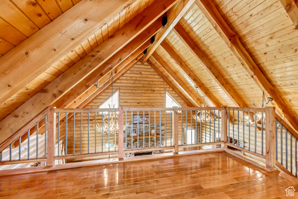 Unfurnished living room featuring wooden ceiling, hardwood / wood-style flooring, a chandelier, and log walls