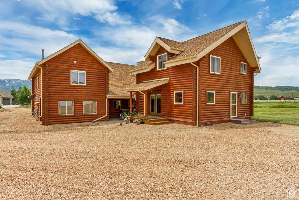 Back of house with a shingled roof and a mountain view