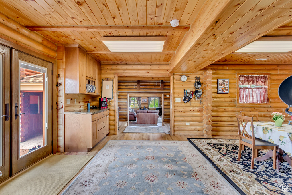 Kitchen with a wood ceiling with exposed beams, light wood-style floors, rustic walls, and healthy amount of natural light
