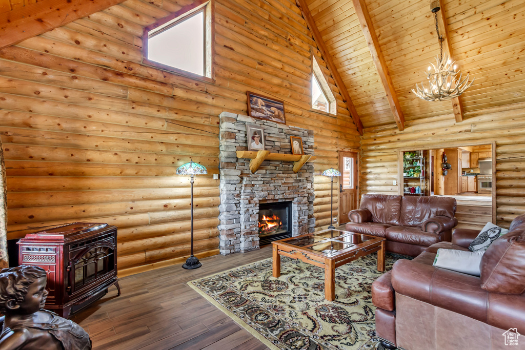 Living area featuring high vaulted ceiling, a wood stove, a chandelier, log walls, and a fireplace