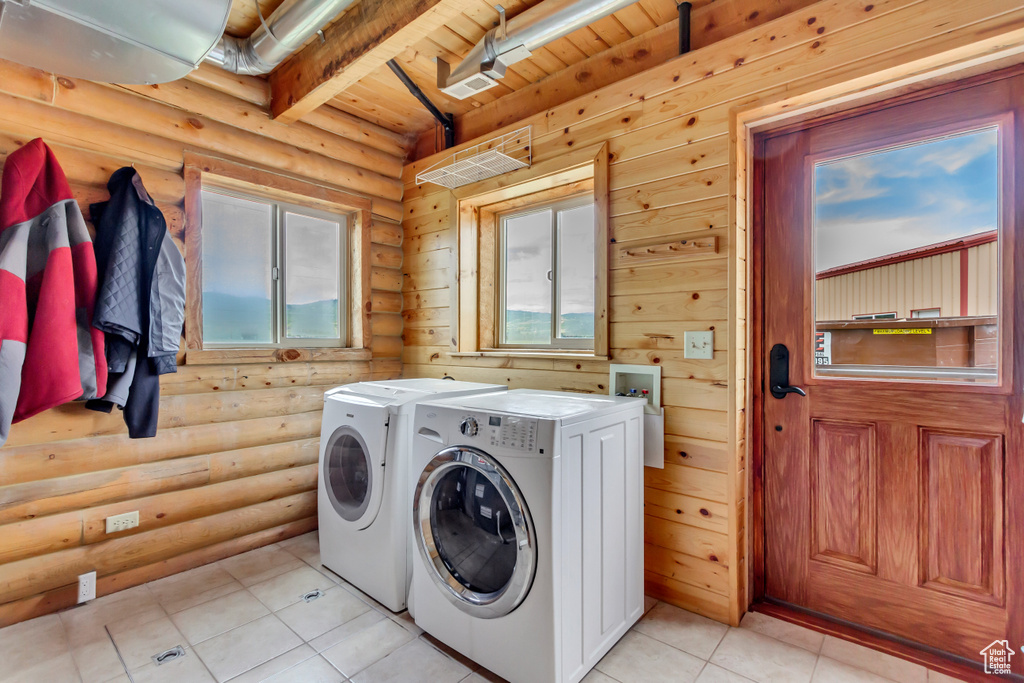 Washroom with washing machine and dryer, log walls, wood ceiling, and light tile patterned floors