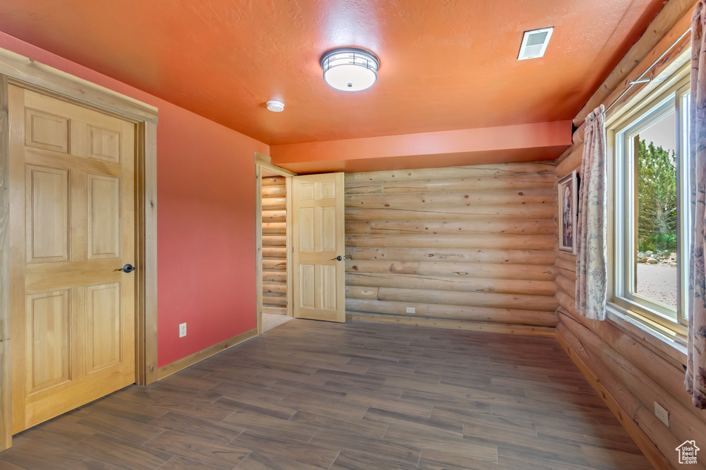 Spare room with log walls, a smoke detector, and dark wood-style flooring