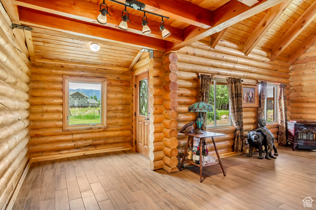 Empty room with a wooden ceiling with exposed beams, rustic walls, and wood finished floors