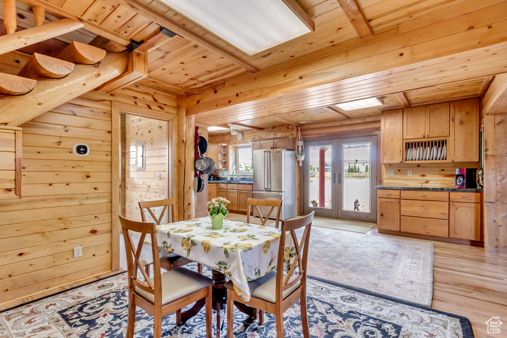 Dining space with wooden ceiling, wood walls, light wood-type flooring, and french doors