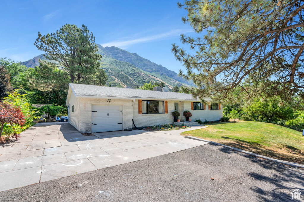 Ranch-style house with a mountain view, brick siding, a garage, and driveway