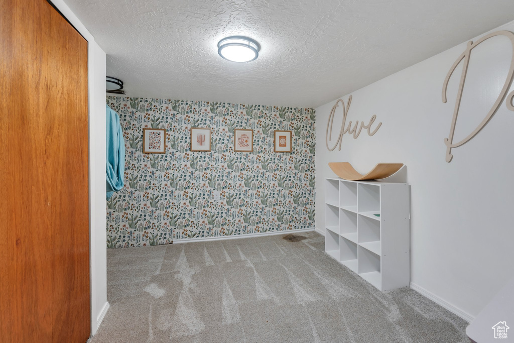 Empty room with wallpapered walls, carpet floors, and a textured ceiling
