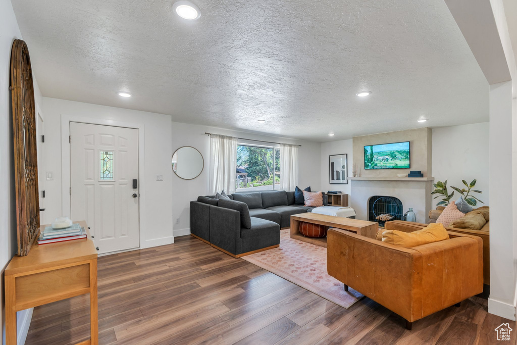 Living area with a textured ceiling, dark wood-style flooring, recessed lighting, and a large fireplace
